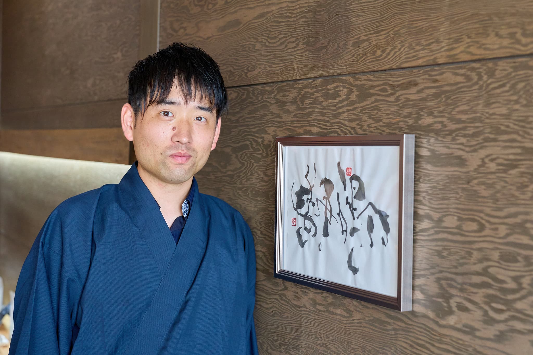 「静鳴（せいな）」と同じ額装作品の横に立つ、紺の着物姿の森下友喜