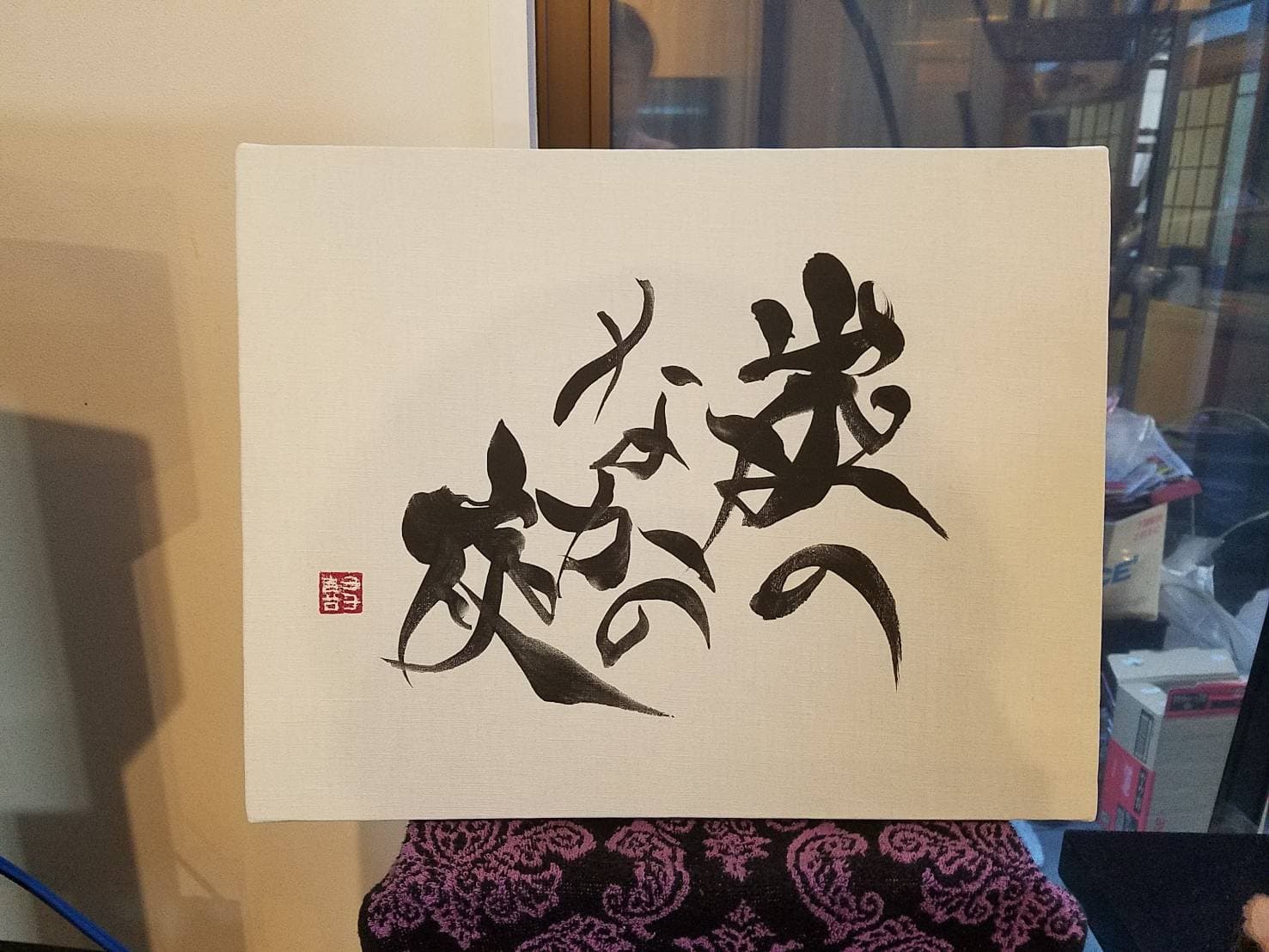 布張りのパネルに草書で綴った作品。左下に朱の落款を配する