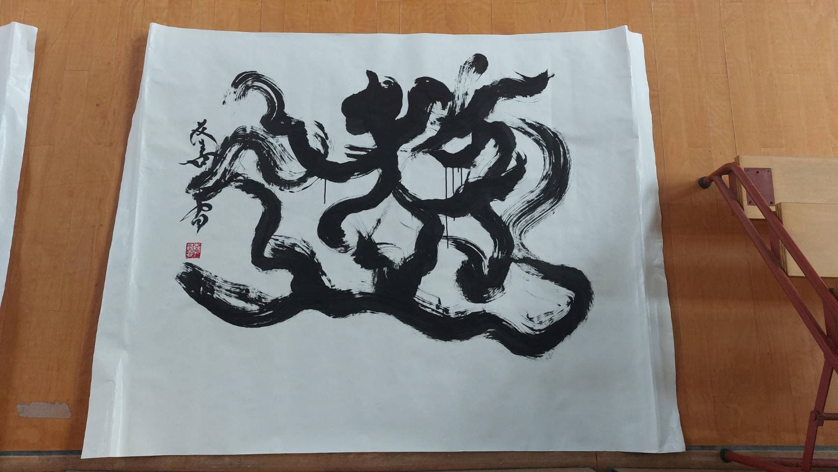 板張りの床に広げた大判の紙に、勢いのある筆致で書いた大字